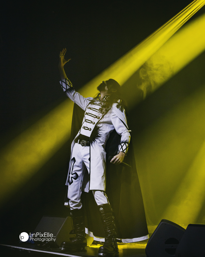 Cape et lumière dorée: le chanteur domine la scène comme une apparition.